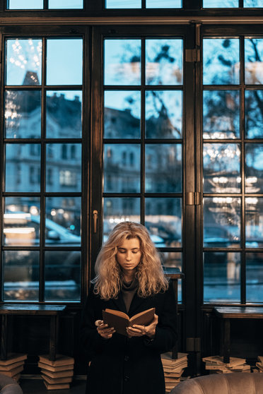 beautiful young woman reading a book while sitting on the couch
