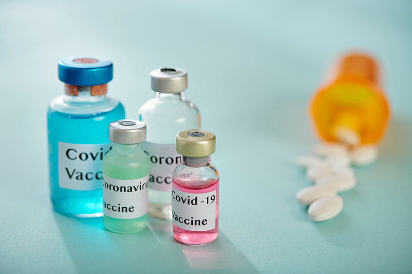 Vials with various types of vaccines against coronavirus and container of pills