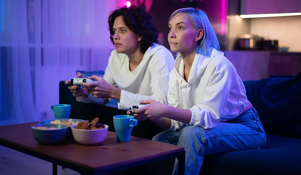 Photo of young couple playing video games at home at night.