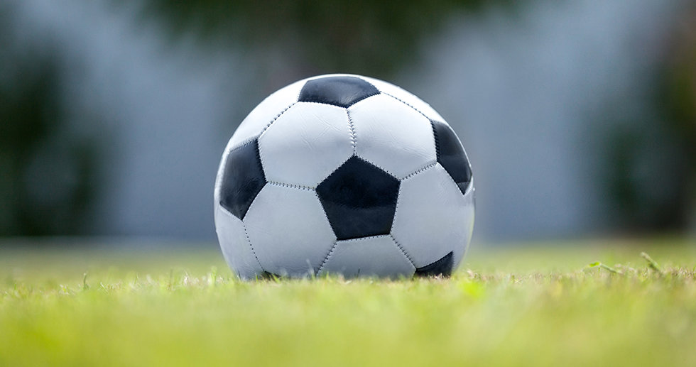 Close-up shot of a soccer ball on green grass. Defocused background and foreground