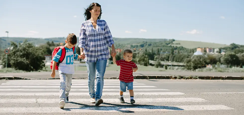 Mother and her children crossing a road on way to school in the morning