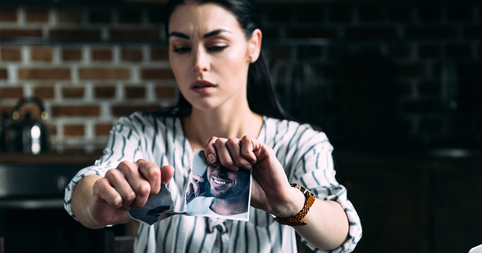 depressed young woman tearing photo of ex-boyfriend
