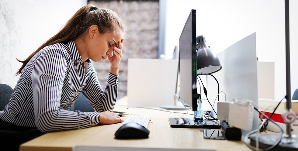 Overworked and frustrated young business woman in front of computer in office